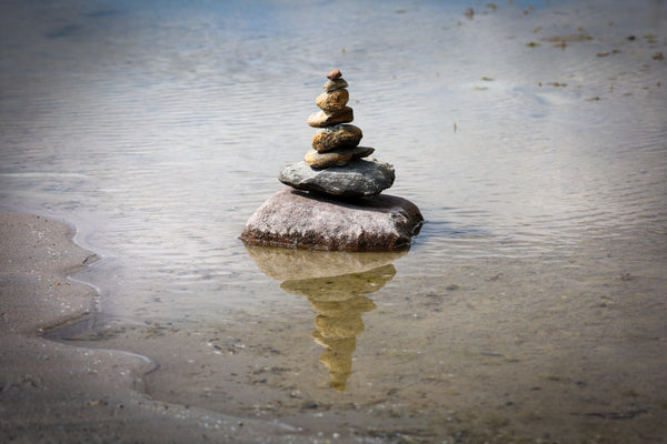 Seven chakra stones balanced in calm water.
