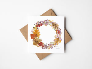 Watercolour greeting card featuring a beautiful autumn wreath with rich oranges, deep reds, and earthy greens. The design evokes the cozy charm and beauty of the fall season, bringing warmth and elegance to any space.