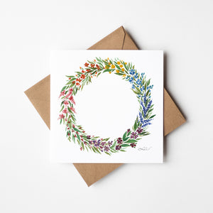 Watercolour print greeting card featuring a spring wreath design with bright colors, fresh green leaves, and vibrant flowers. The card captures the renewal and warmth of the spring season, evoking a sense of nature’s beauty and joy.