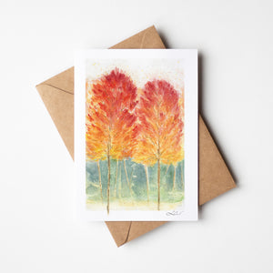 Watercolour greeting card featuring a vibrant autumn forest with rich reds, oranges, and yellows. The design captures the warmth and beauty of the fall season.