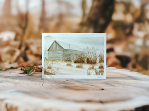 Watercolour greeting card featuring an old barn in the fog, surrounded by tall grass. The soft, misty atmosphere evokes a sense of peaceful solitude and rustic charm.