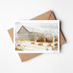 Watercolour greeting card featuring an old barn in the fog, surrounded by tall grass. The soft, misty atmosphere evokes a sense of peaceful solitude and rustic charm.