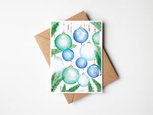Festive Ornaments Greeting Card – Eco-friendly greeting card featuring a delicate watercolour illustration of ornamental balls hanging from a Christmas tree, capturing the magic of the holiday season.