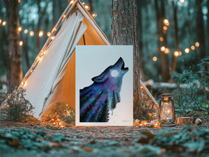 A greeting card featuring a silhouette of a wolf howling at a full moon, set against a backdrop of a vibrant aurora and a starry sky. The design captures the mystical and untamed beauty of the night.