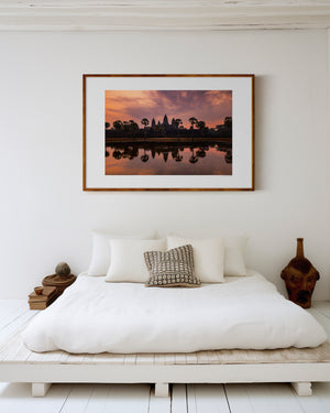 Fine art landscape photograph of Angkor Wat at dawn, with a soft veil of colour, tranquil reflection, and atmospheric light surrounding the temple silhouette.