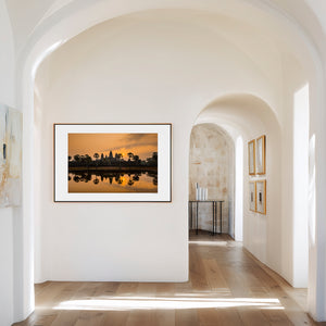 Fine art landscape photograph of Angkor Wat at sunrise, with golden light, sun mirrored in still water, and a serene, atmospheric temple silhouette.