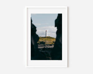 Fine art photography print featuring a lone lighthouse against Iceland's rugged coastal scenery.