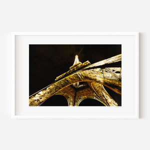 Fine art photograph of the Eiffel Tower at night, glowing against the Parisian sky in a romantic, luminous scene.