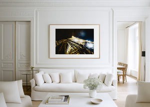 Fine art photograph of the Eiffel Tower at night, showing sparkling, bursting lights against the Parisian sky.