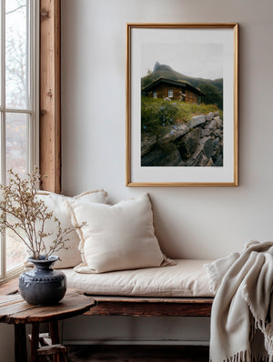 Dreamy hidden wooden cabin beneath a mountain in Norway, moody fine art landscape photography print.