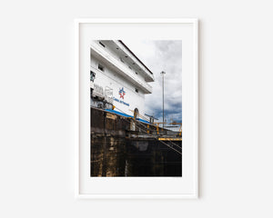 Angled view of the Panama Canal locks showing the Canal de Panamá sign and a locomotive moving the lock doors in a fine art photograph.