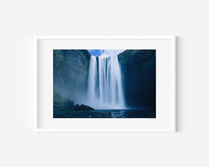 Fine art photograph of Skogafoss waterfall in Iceland, capturing its powerful vertical drop and mist in dramatic natural light.