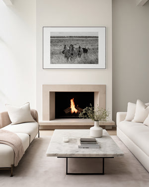 A line of zebras moving steadily across Ngorongoro grasslands, accompanied by a lone wildebeest, captured in a fine art wildlife photograph.